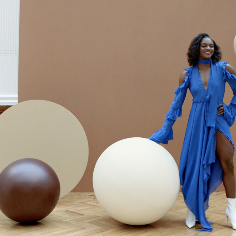 A woman in a blue dress surrounded by giant chocolate and white chocolate covered balls