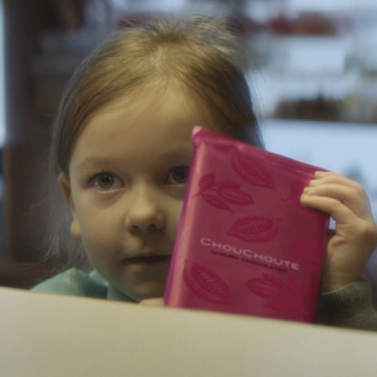 Closeup of a little girl holding a pink packaged chocolate bar